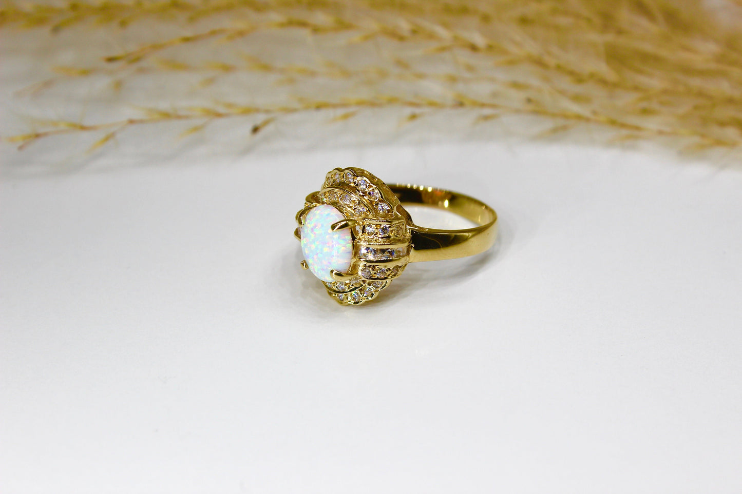 Opal oval in 14K yellow gold surrounded by zirconia stones in 4-claw setting