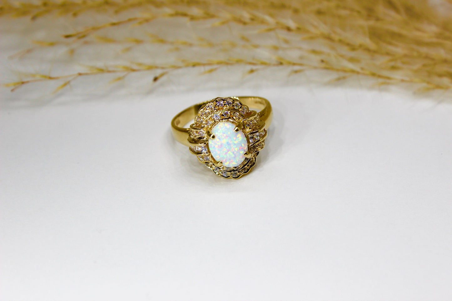 Opal oval in 14K yellow gold surrounded by zirconia stones in 4-claw setting