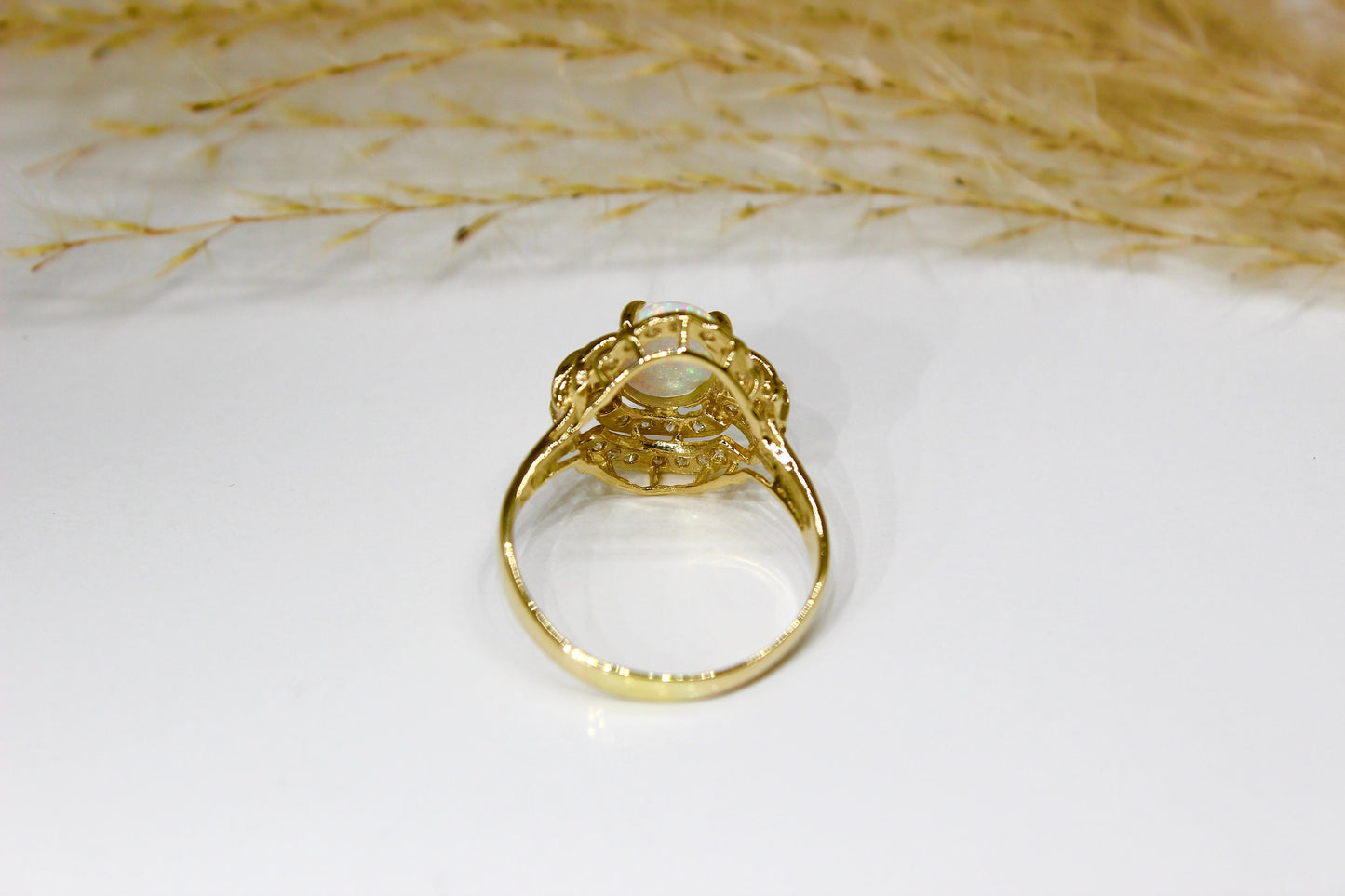 Opal oval in 14K yellow gold surrounded by zirconia stones in 4-claw setting