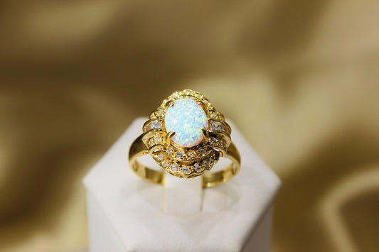 Opal oval in 14K yellow gold surrounded by zirconia stones in 4-claw setting